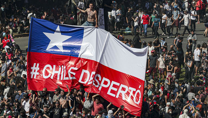 Fotografía de una manifestación con una bandera chilena que dice: Chile despertó