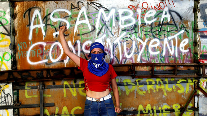 Manifestante con el puño en alto exigiendo una Asamblea Constituyente