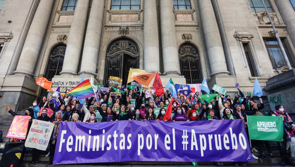 Captura de ecran de imagen de mujeres frente a la Biblioteca nacional con un lienzo que dice: feministas por el apruebo